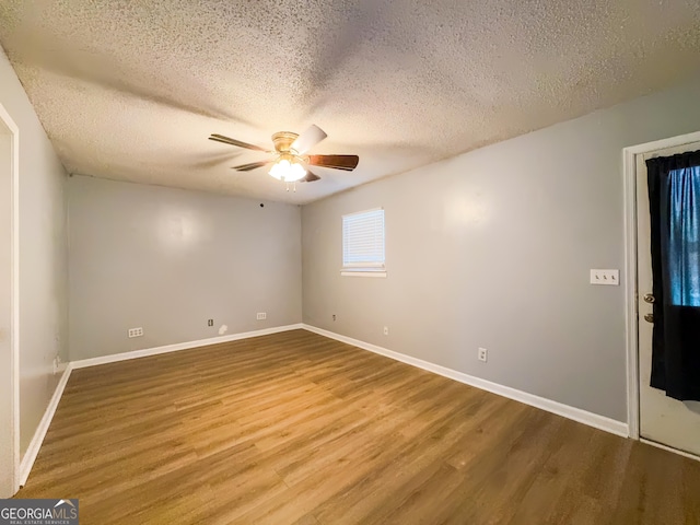 empty room featuring ceiling fan, wood-type flooring, and a textured ceiling