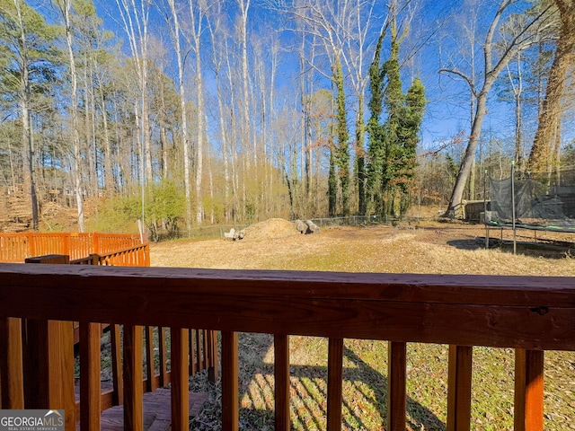 view of yard featuring a trampoline and a wooden deck