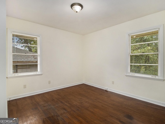 empty room with dark hardwood / wood-style flooring and a healthy amount of sunlight