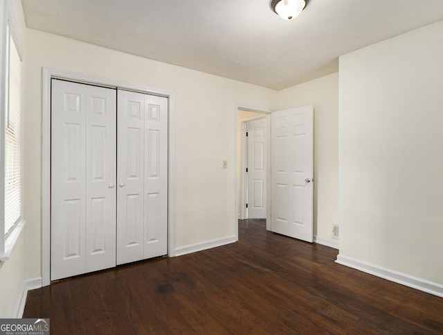 unfurnished bedroom with dark wood-type flooring and a closet