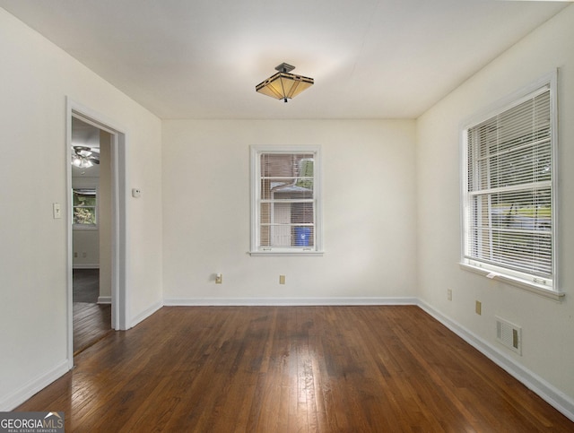 spare room with dark wood-type flooring and a wealth of natural light