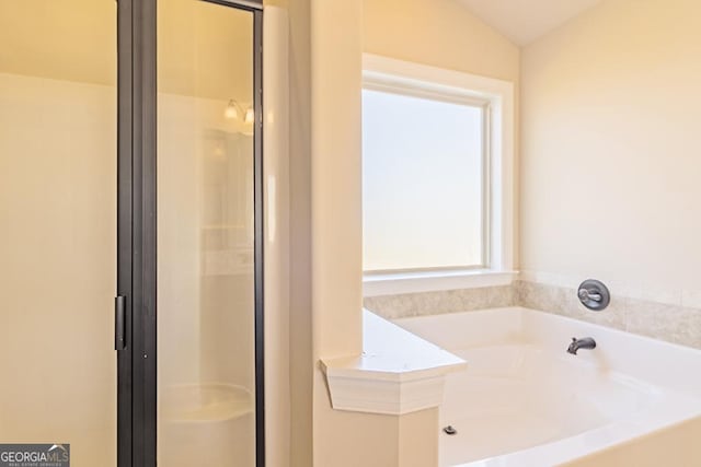 bathroom with a washtub and vaulted ceiling