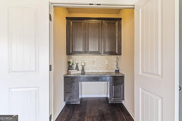 bar featuring light stone counters, dark brown cabinetry, dark hardwood / wood-style floors, and decorative backsplash