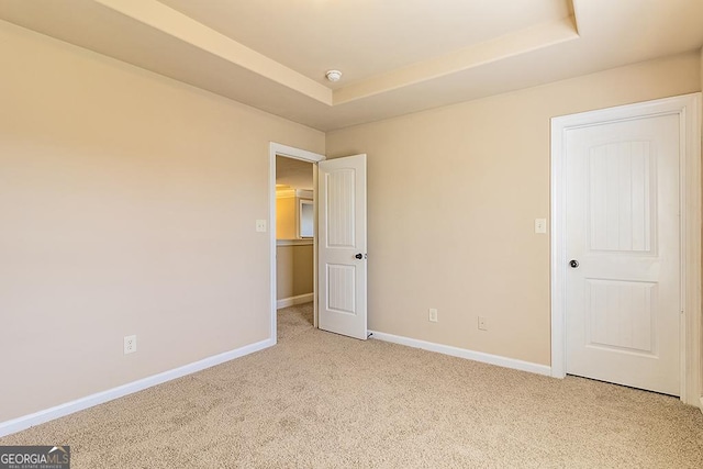 unfurnished room featuring light carpet and a tray ceiling