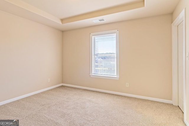 carpeted spare room featuring a tray ceiling