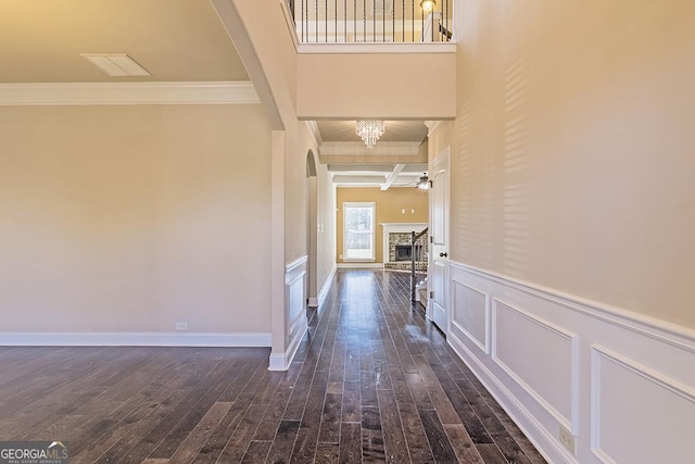 corridor featuring crown molding, dark hardwood / wood-style floors, beam ceiling, and a notable chandelier