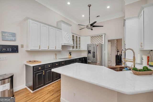 kitchen with stainless steel fridge, a peninsula, black electric stovetop, crown molding, and a sink