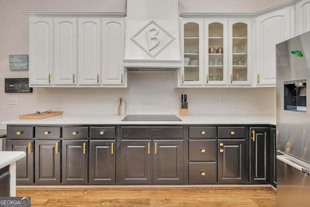 kitchen featuring light countertops, white cabinets, stainless steel fridge, and black electric cooktop