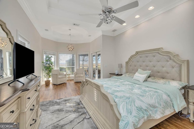 bedroom featuring visible vents, a tray ceiling, wood finished floors, and ornamental molding