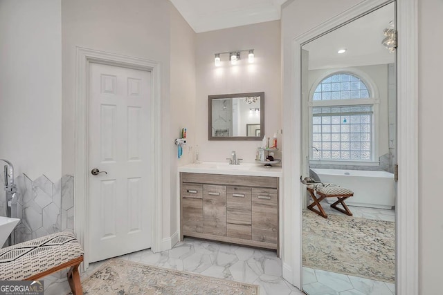 bathroom featuring marble finish floor, a freestanding tub, and vanity