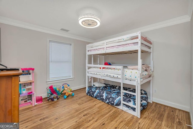 bedroom featuring crown molding, baseboards, and wood finished floors