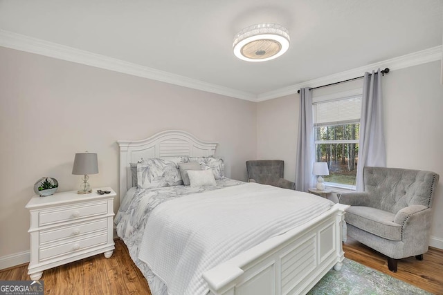 bedroom featuring crown molding, baseboards, and wood finished floors