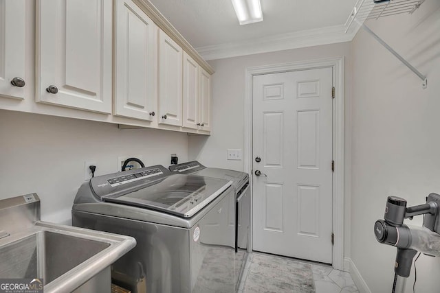 laundry room featuring cabinet space, marble finish floor, crown molding, washing machine and dryer, and a sink