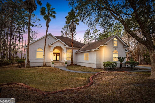 view of front of home featuring a lawn and stucco siding