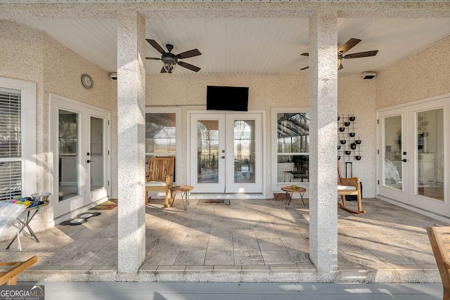 view of exterior entry featuring stucco siding, ceiling fan, a patio, and french doors