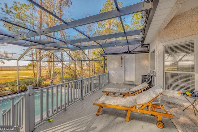 wooden terrace with a lanai and an outdoor pool