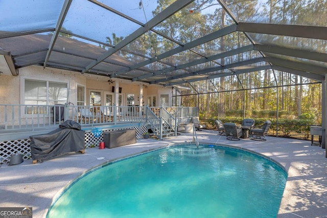 pool featuring glass enclosure, a patio area, and a wooden deck