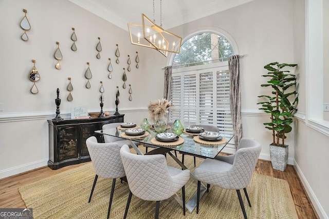 dining area featuring a chandelier, crown molding, baseboards, and wood finished floors