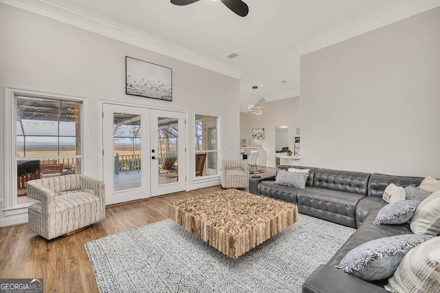 living room with a ceiling fan, ornamental molding, wood finished floors, a high ceiling, and french doors