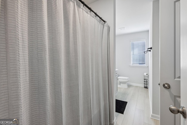 bathroom with hardwood / wood-style flooring and toilet