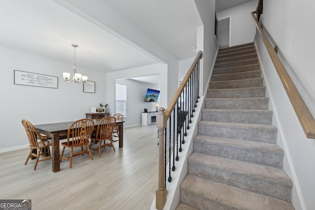 stairs with wood-type flooring and a chandelier