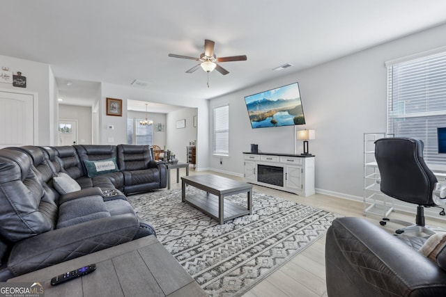 living room with ceiling fan with notable chandelier and light hardwood / wood-style floors