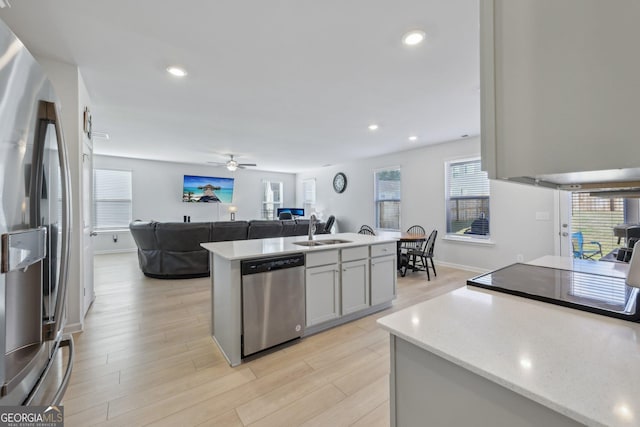 kitchen featuring sink, a center island, ceiling fan, stainless steel appliances, and light hardwood / wood-style flooring