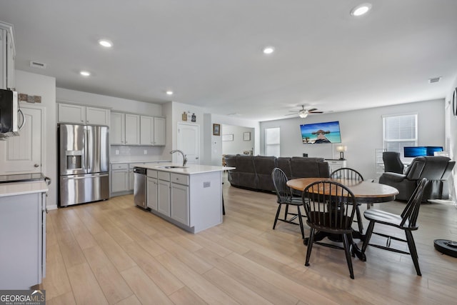 kitchen featuring sink, a kitchen island with sink, a wealth of natural light, stainless steel appliances, and light hardwood / wood-style floors