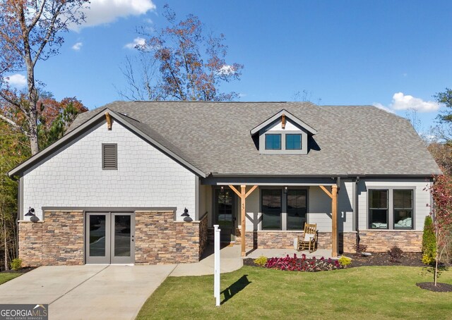 view of front of property with french doors, stone siding, a front yard, and a shingled roof