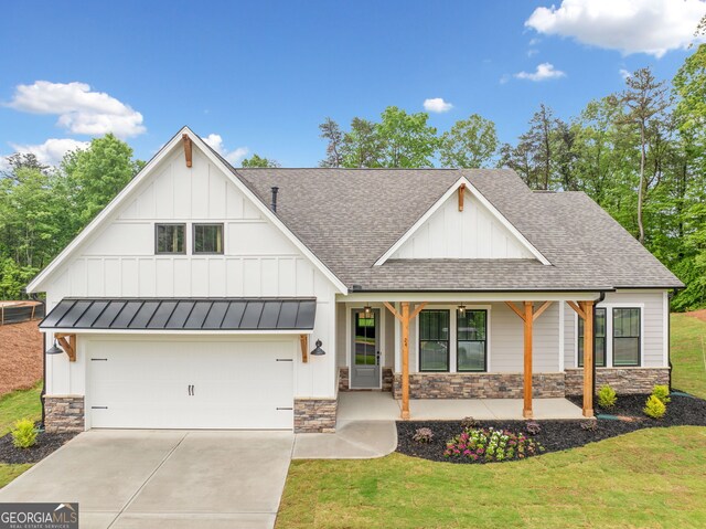 modern inspired farmhouse featuring a front lawn, covered porch, stone siding, a shingled roof, and board and batten siding