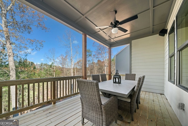 wooden deck with outdoor dining area and ceiling fan