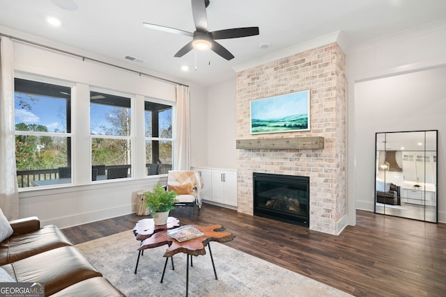 living room featuring wood finished floors, baseboards, visible vents, a fireplace, and ornamental molding