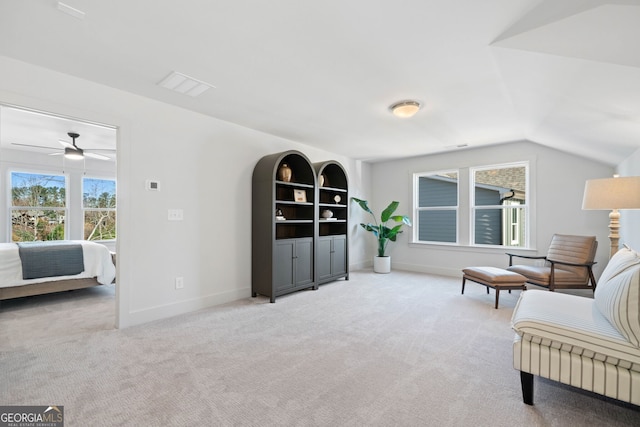 living area featuring visible vents, carpet floors, baseboards, ceiling fan, and vaulted ceiling