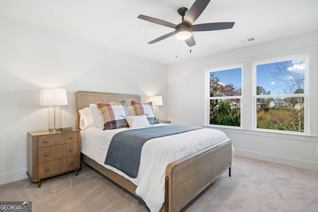 bedroom with a ceiling fan, baseboards, visible vents, and light carpet