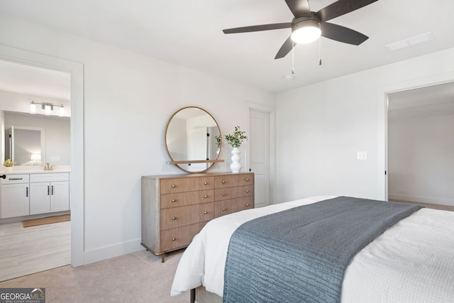 bedroom featuring a ceiling fan, visible vents, baseboards, ensuite bath, and light carpet