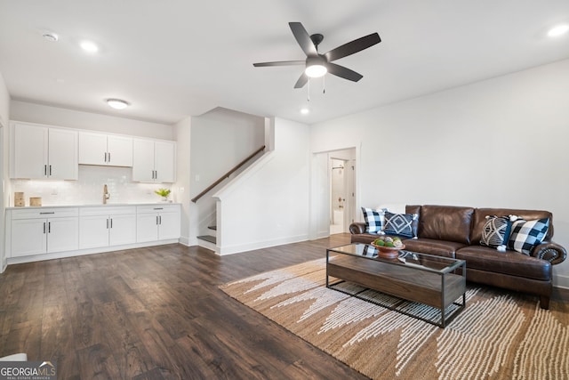 living area featuring baseboards, stairs, dark wood-type flooring, and a ceiling fan