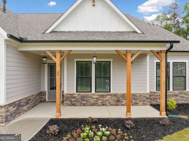 property entrance with roof with shingles, board and batten siding, and stone siding