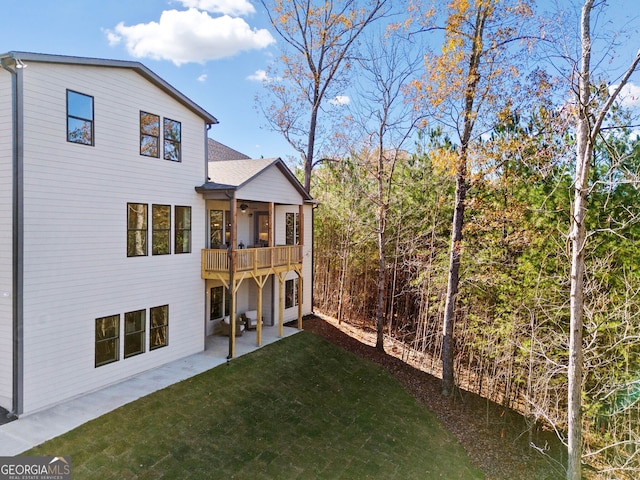 back of house featuring a yard, a shingled roof, and a patio