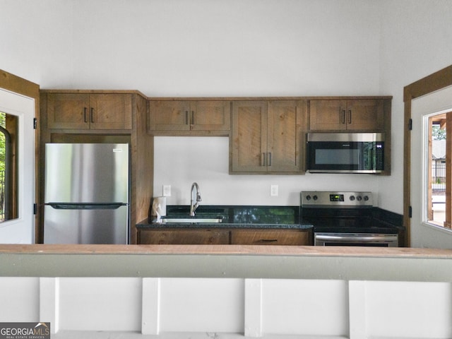 kitchen featuring a sink, dark countertops, a wealth of natural light, and stainless steel appliances