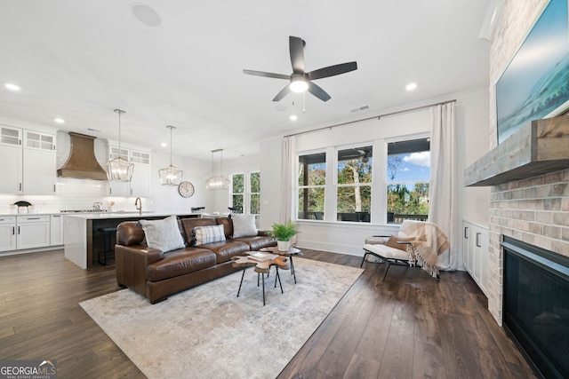 living room with recessed lighting, dark wood-style floors, a fireplace, and ceiling fan with notable chandelier