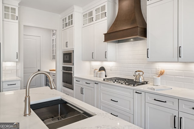 kitchen with a sink, decorative backsplash, custom exhaust hood, and appliances with stainless steel finishes