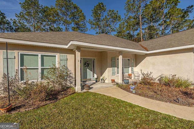 exterior space with stucco siding, roof with shingles, and a front lawn