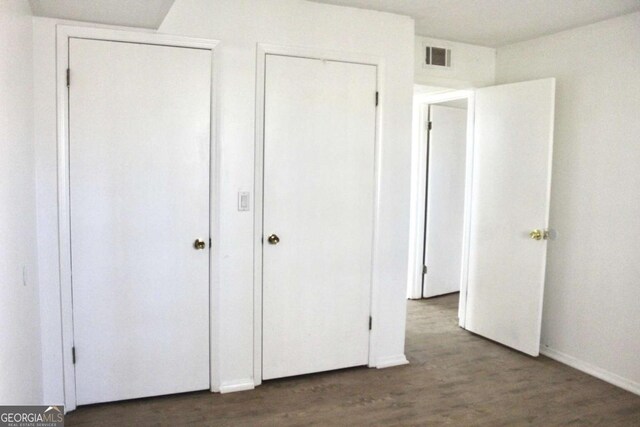 507 Augusta Dr SE, Marietta, GA 30067 - unfurnished bedroom featuring dark wood-type flooring and two closets
