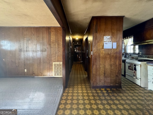 interior space featuring electric stove, beam ceiling, and wood walls