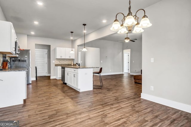 kitchen with a kitchen island, appliances with stainless steel finishes, white cabinetry, dark stone countertops, and hanging light fixtures