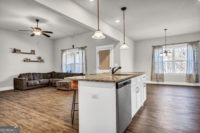 kitchen with sink, decorative light fixtures, dark stone countertops, stainless steel dishwasher, and white cabinets