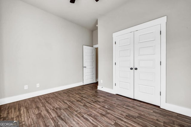 unfurnished bedroom with dark hardwood / wood-style flooring, a closet, and ceiling fan