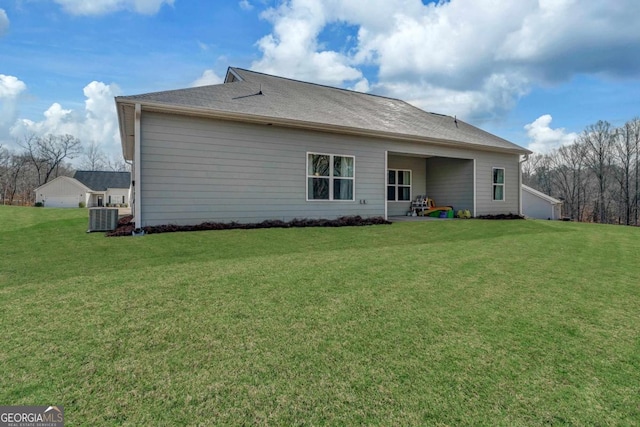 rear view of house with central AC and a lawn