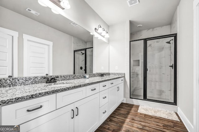 bathroom featuring vanity, wood-type flooring, and a shower with shower door