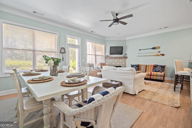 interior space featuring crown molding, ceiling fan, a fireplace, and light wood-type flooring